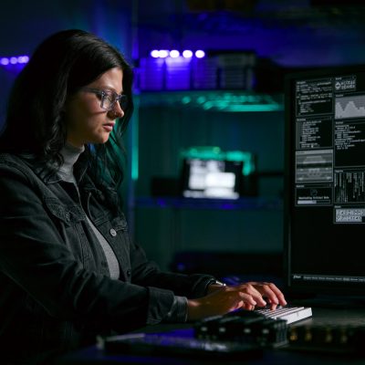 female student at a keyboard programming with multiple monitors